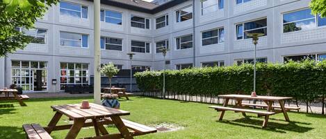 A courtyard with picnic tables and a building with multiple windows and balconies.