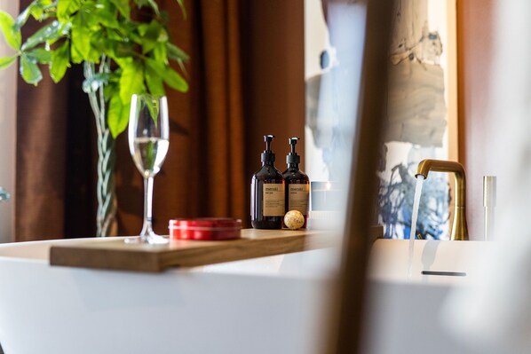 A table with two wine bottles, a glass, and a red container.