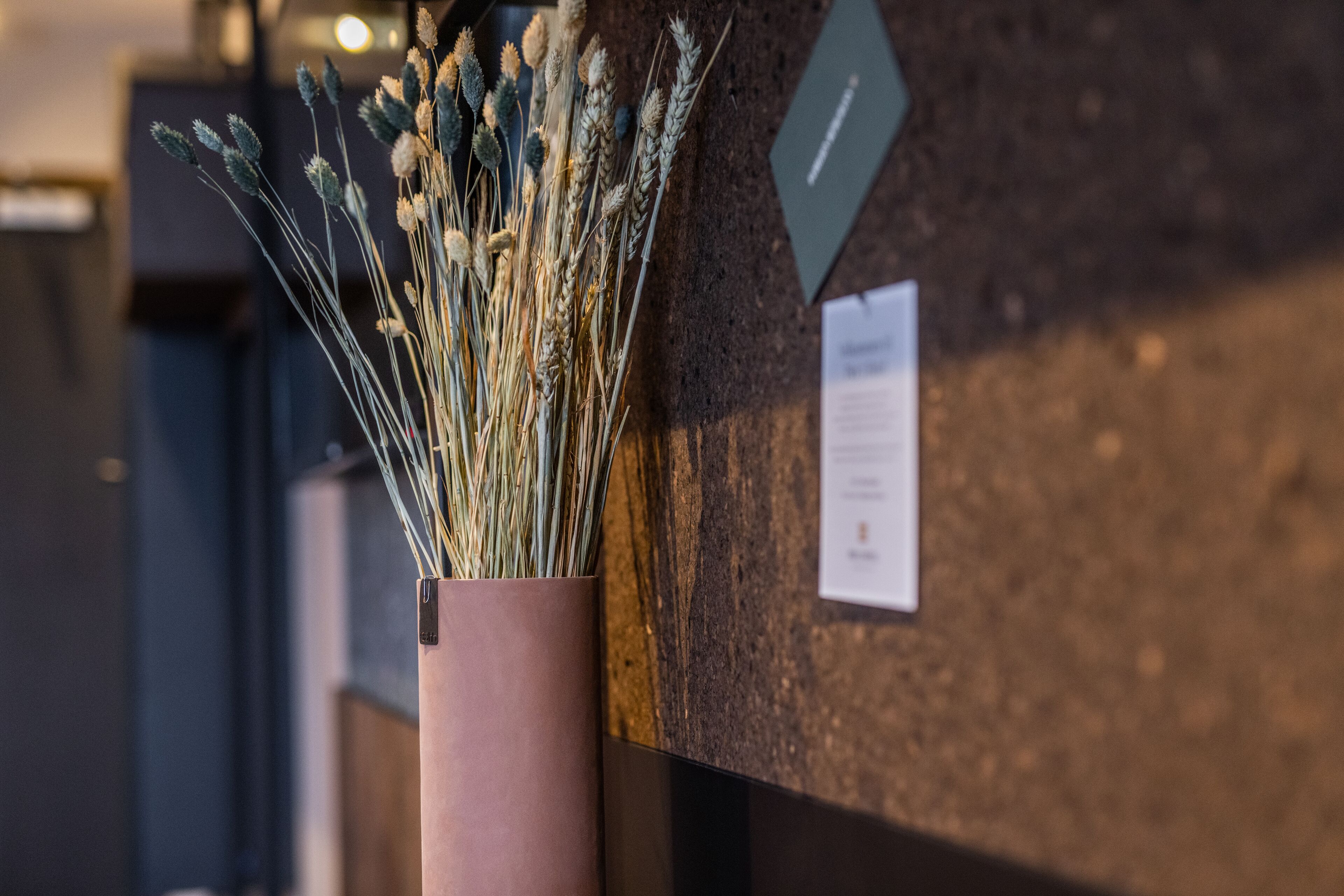 A vase with dried plants on a wall.