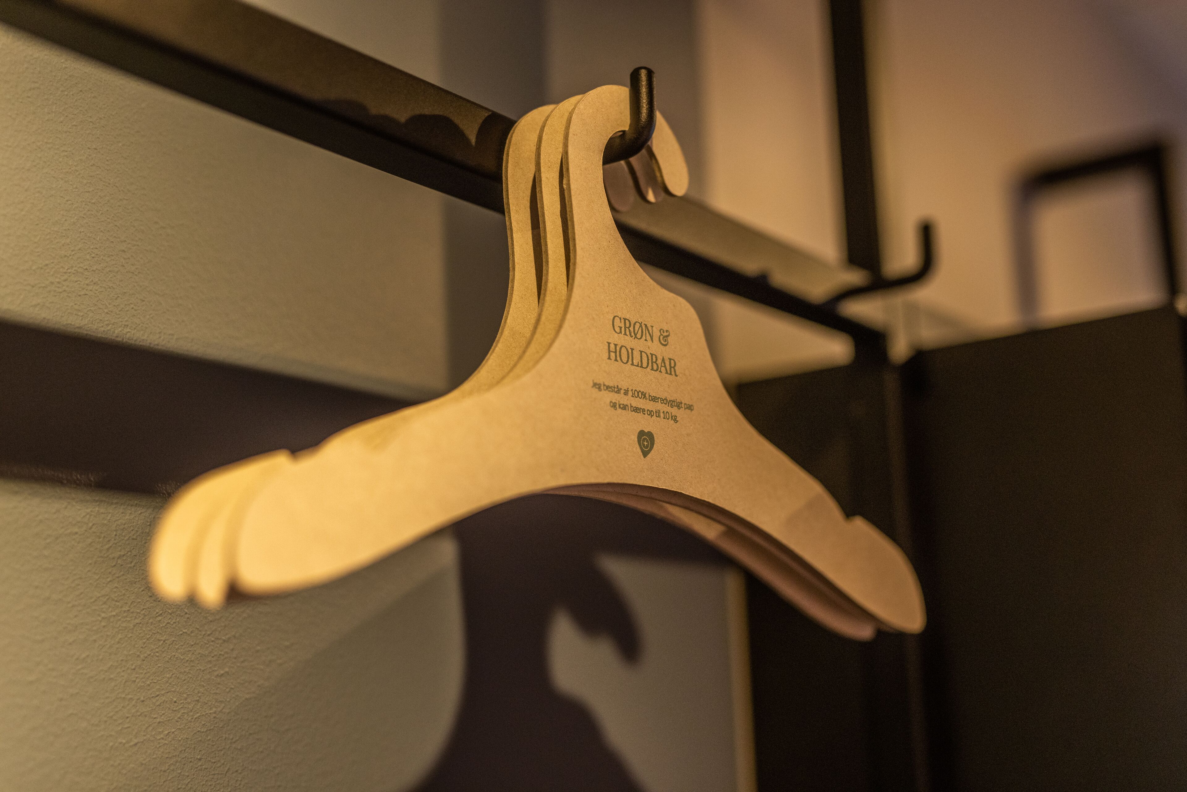Un cintre en bois portant une inscription, suspendu à une tige métallique.