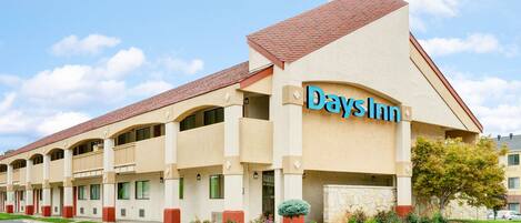 Un hotel Days Inn con fachada color beige, techo rojo y varios balcones.