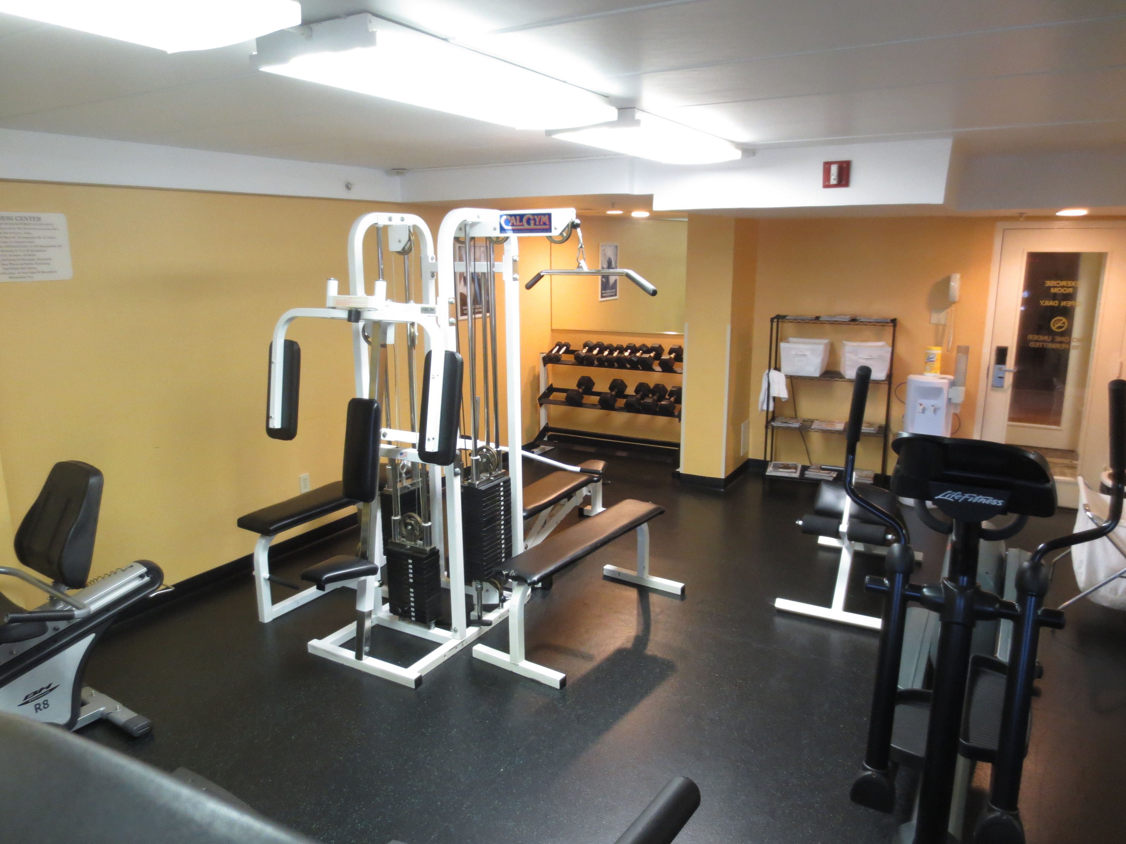 Un gimnasio con equipo de ejercicio variado, incluyendo una banca, máquinas de pesas y una cinta de correr.