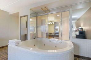 A modern bathroom with a large freestanding bathtub, a glass-enclosed shower area, and a visible sink and mirror.