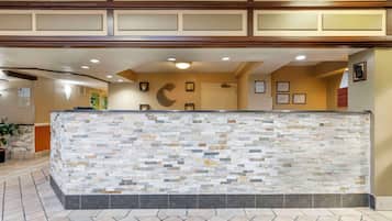 A reception area with a stone-textured counter, framed certificates on the wall, and a potted plant.