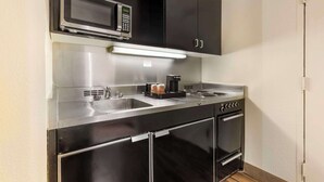 A compact kitchen with a microwave, coffee maker, and a stove.
