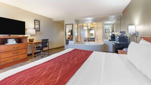 A hotel room with a bed, a desk, a chair, a television, a bathroom with a bathtub, and a coffee machine.