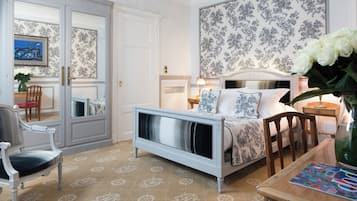 Een slaapkamer met een bed, een stoel, een tafel en een spiegel.