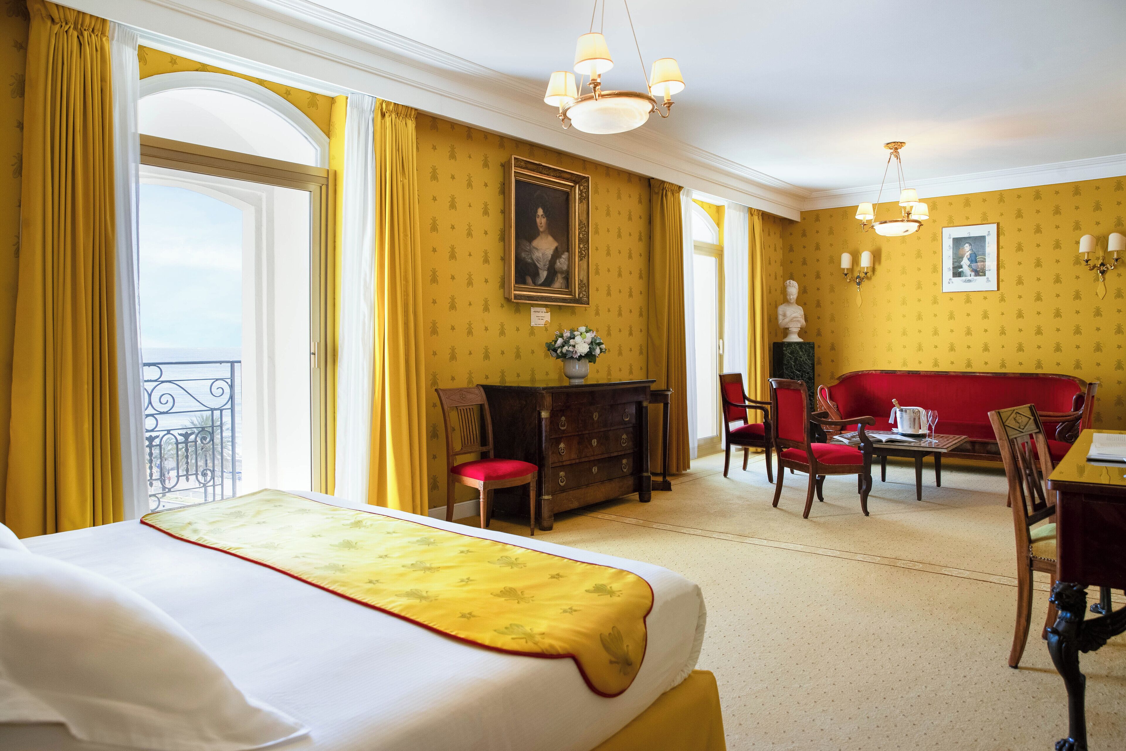 Une chambre d’hôtel avec un lit, un canapé, une table à manger et un balcon.