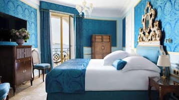 Een slaapkamer met een groot bed, een houten garderobe, een televisie en een kroonluchter.