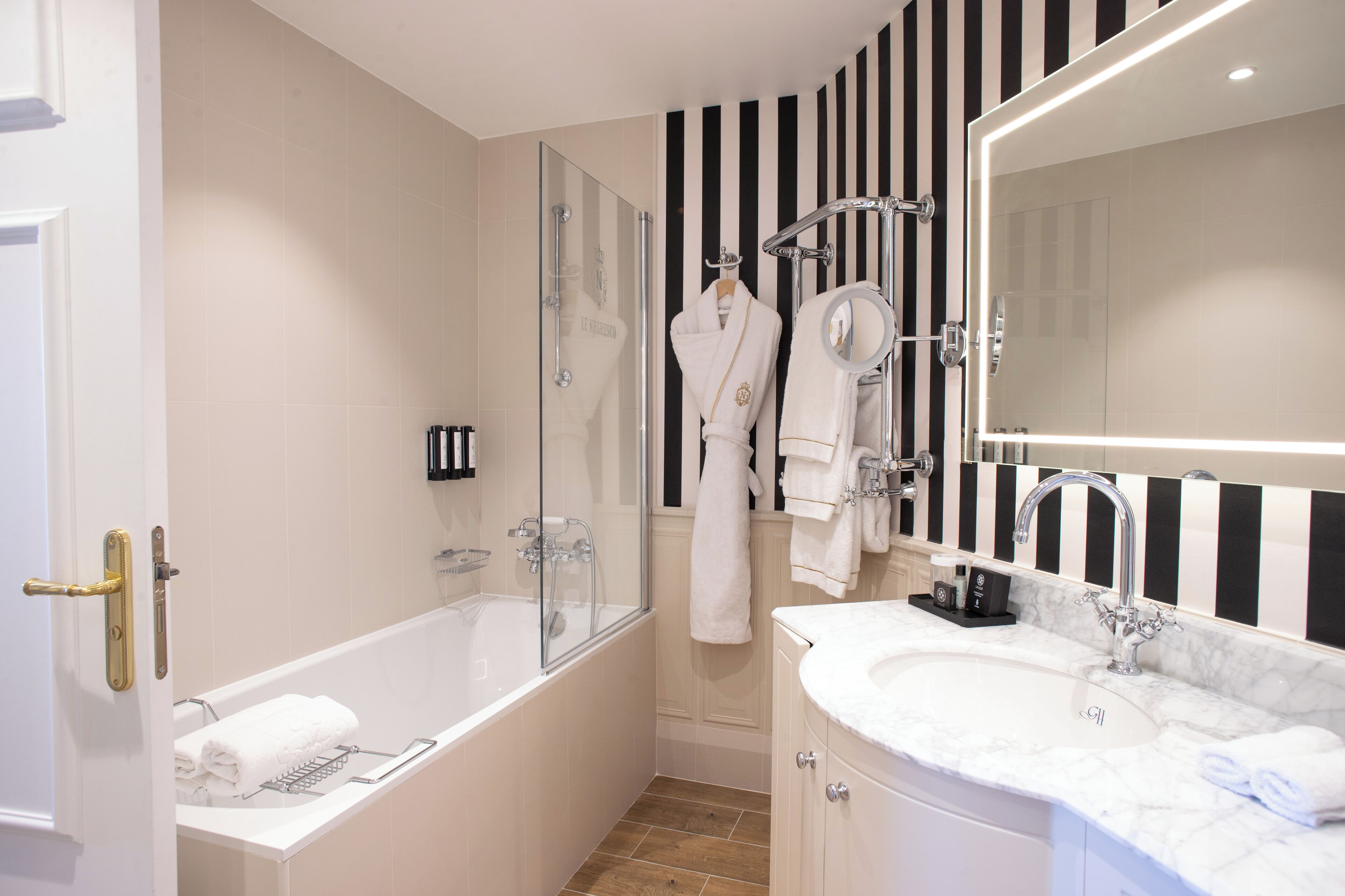 A modern bathroom with a bathtub, a shower, a vanity with a sink, and a large mirror.