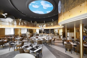 Un restaurant moderne doté d’un bar central, de plusieurs espaces de restauration et d’une grande verrière.