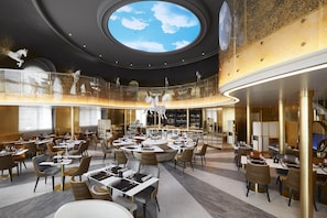 Un restaurante moderno con barra central, varias zonas de comedor y un amplio tragaluz.