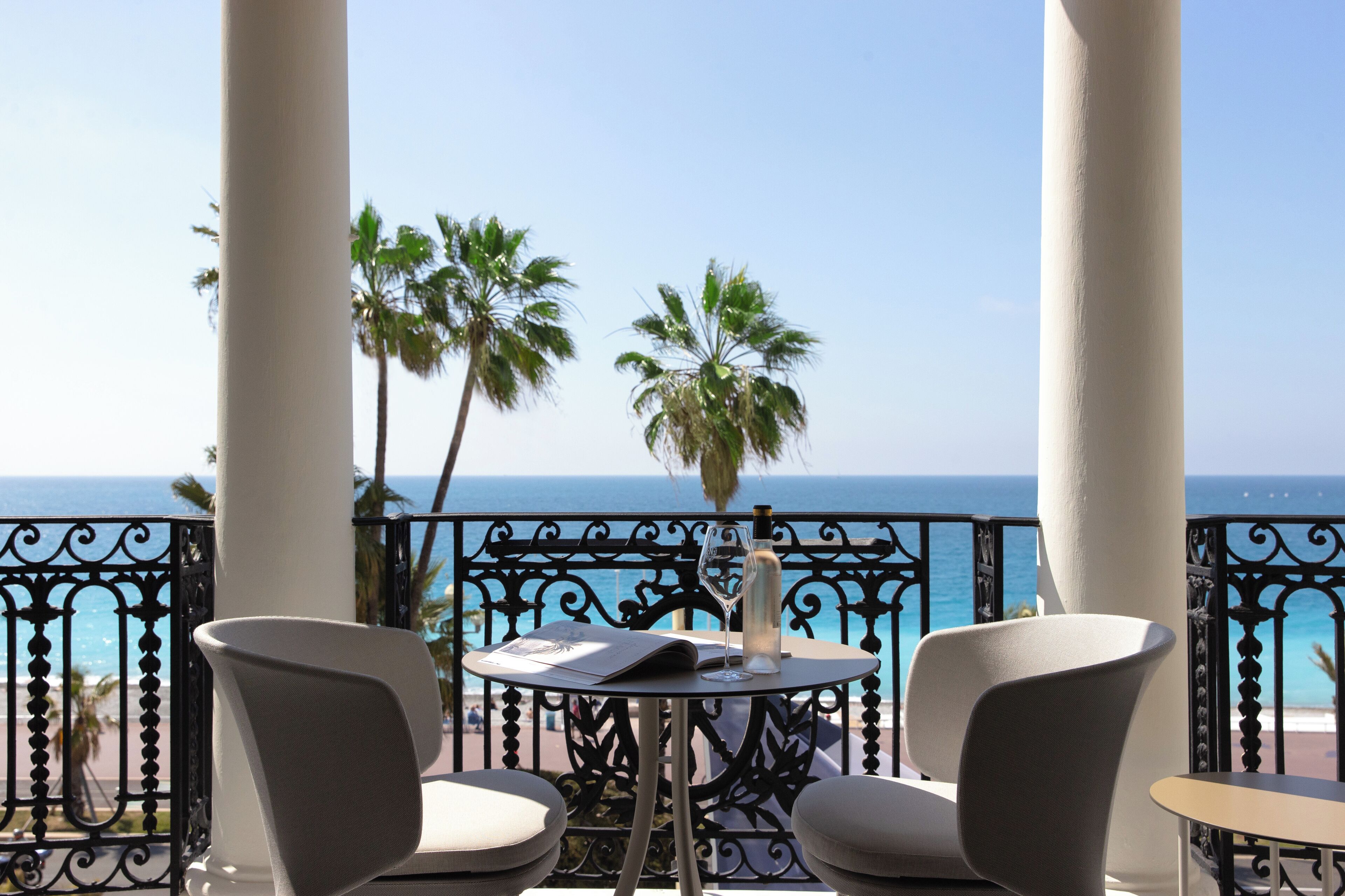 Un balcon avec une table et des chaises, donnant sur une plage et l’océan.