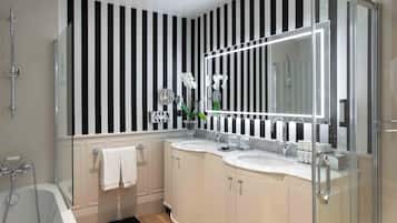 Un baño moderno con pared a rayas negras y blancas, un espejo grande, dos lavamanos y una ducha.