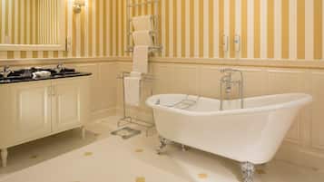 A bathroom with a freestanding bathtub, a vanity with a mirror, and striped wallpaper.