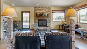 A spacious living room with a stone fireplace, comfortable seating, and large windows. - Best Western Sunset Inn (Cody)