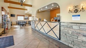 A hotel lobby with a reception desk, seating area, and a staircase leading to upper floors. - Best Western Sunset Inn (Cody)