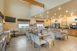 A cafe with multiple tables and chairs, a coffee machine, and a counter with a menu. - Best Western Sunset Inn (Cody)