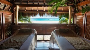 Una habitación con dos camas, vista a la playa y techo de paja.
