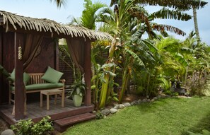 A wooden structure with a thatched roof, a wooden bench with green cushions, and a potted plant. - Manchebo Beach Resort and Spa (Oranjestad)