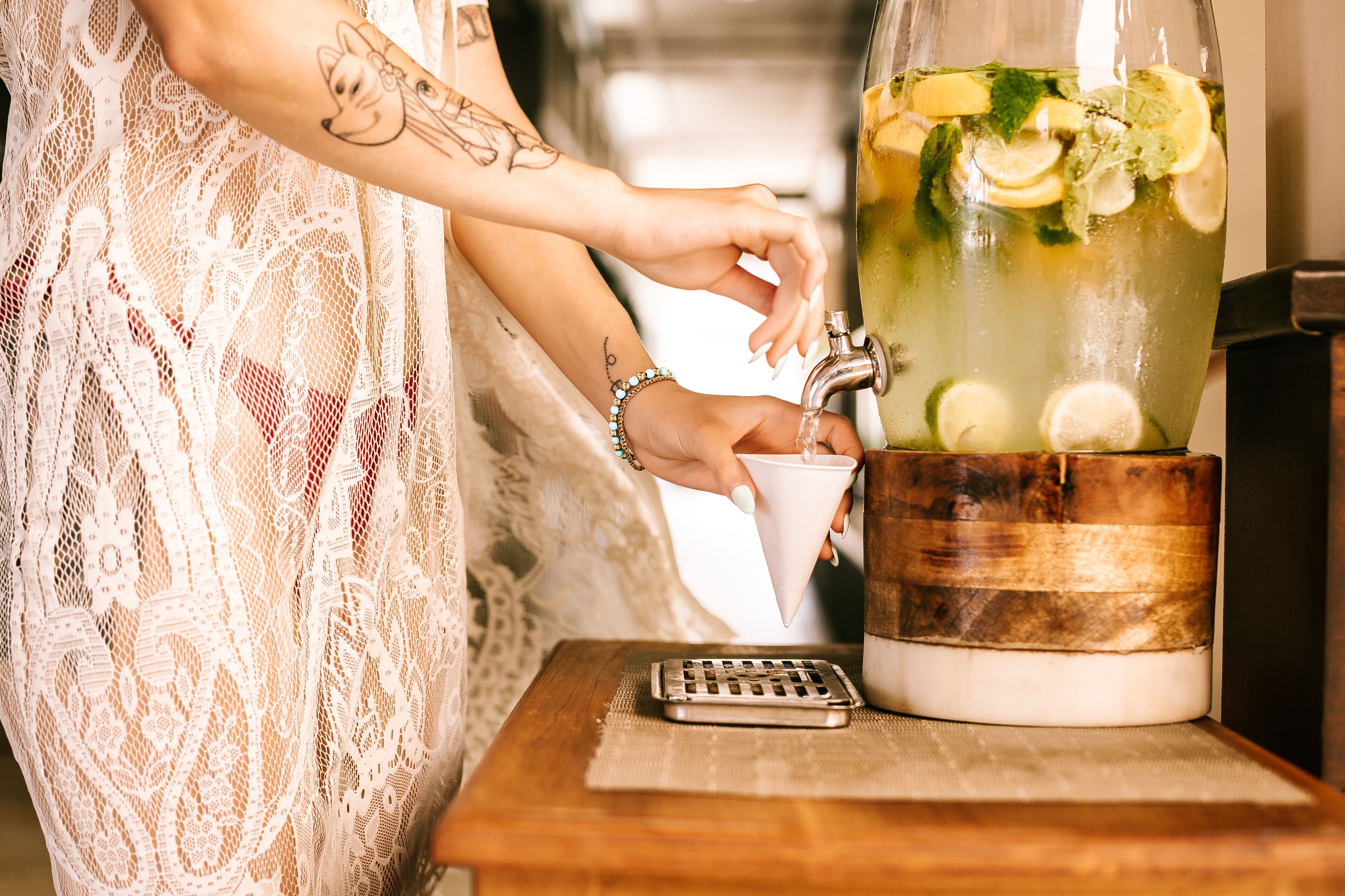 A person pouring a drink from a pitcher into a cup.