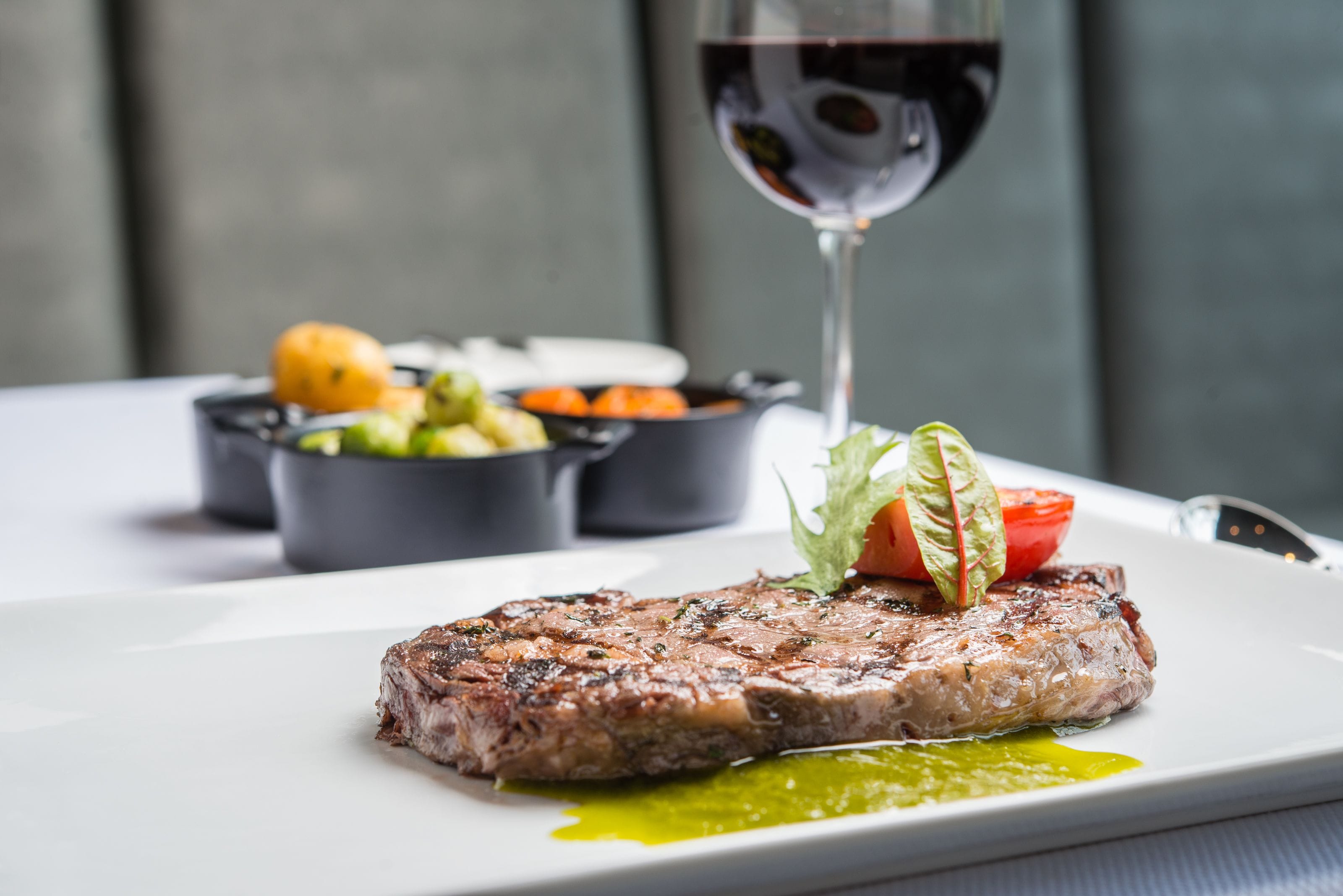 A plate with a steak, vegetables, and a glass of red wine.