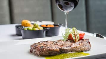 A plate with a steak, vegetables, and a glass of red wine.