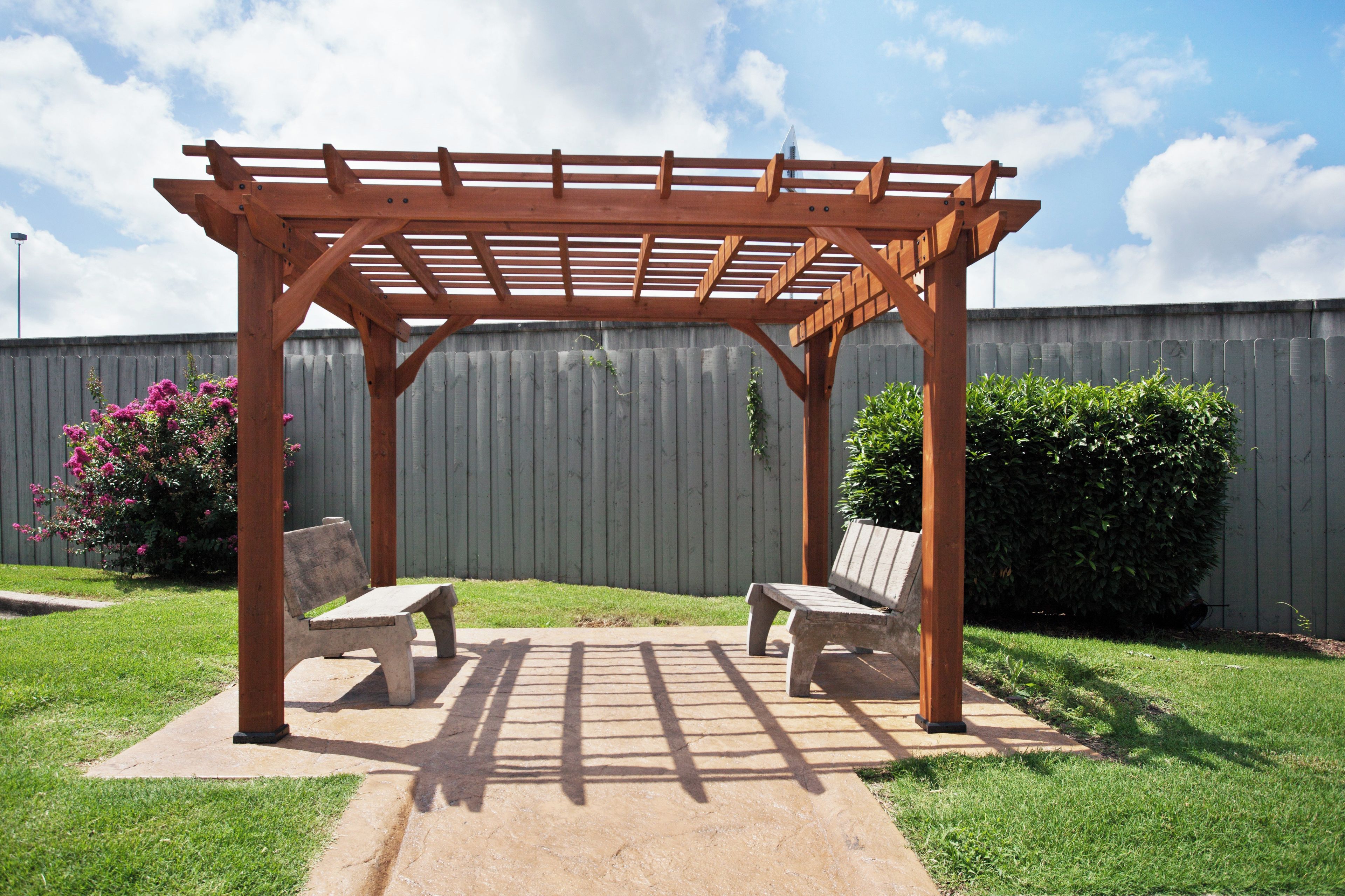 Une pergola en bois avec deux bancs dans un jardin.