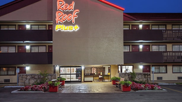A Red Roof Plus hotel with a two-story structure, a front entrance, and a parking lot.