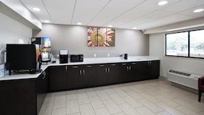 A modern kitchen with a coffee machine, a microwave, and a juice dispenser.