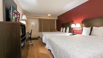 Een hotelkamer met een bed, nachtlampjes, een televisie, een bureau en een stoel.
