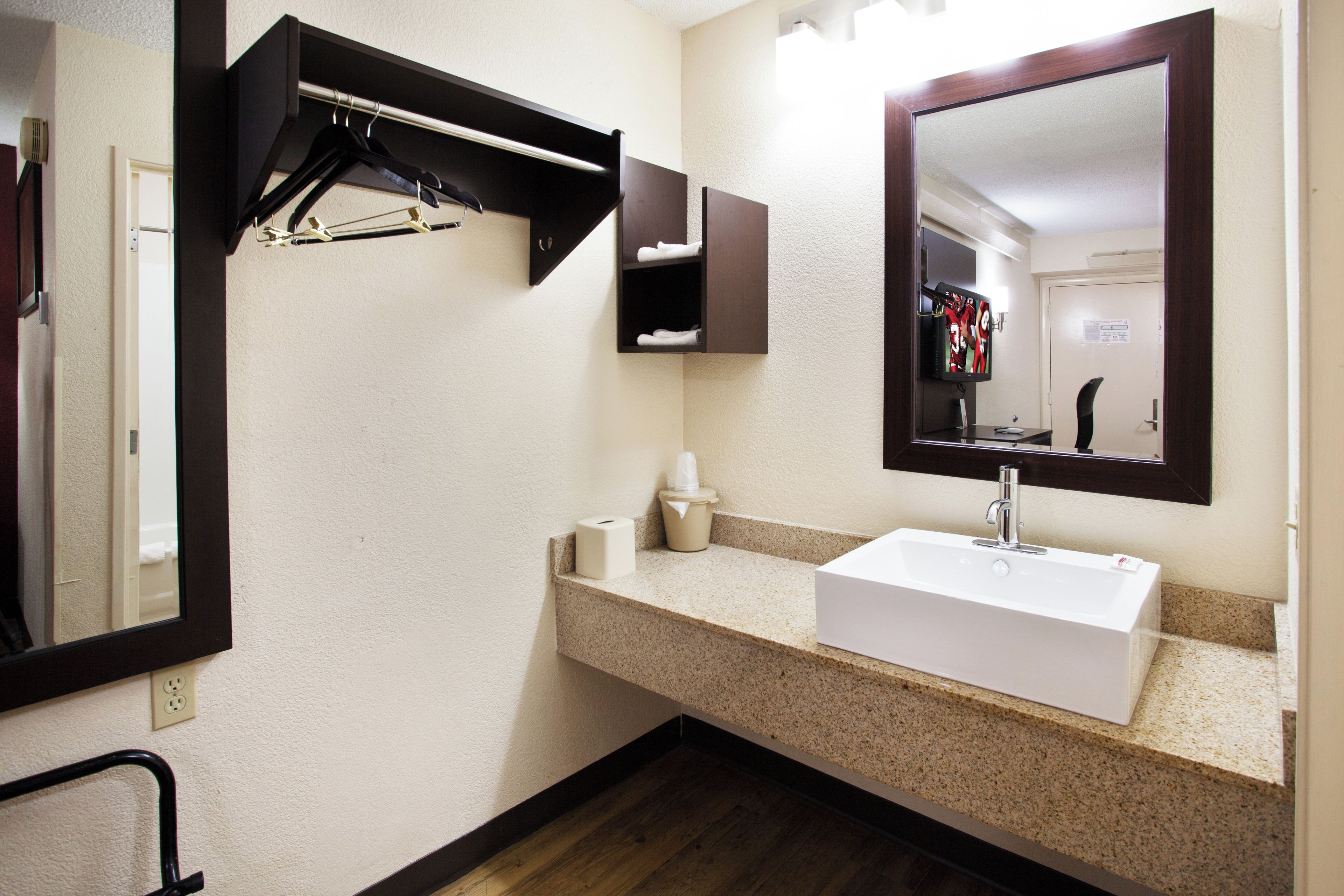 A bathroom with a white sink, a mirror, a towel rack, and a toilet paper holder.