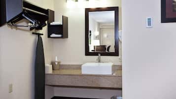 A bathroom with a sink, mirror, towel rack, and a trash bin.