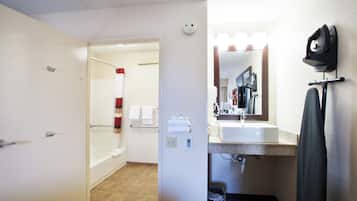 A bathroom with a shower, a sink, a mirror, and a towel rack.