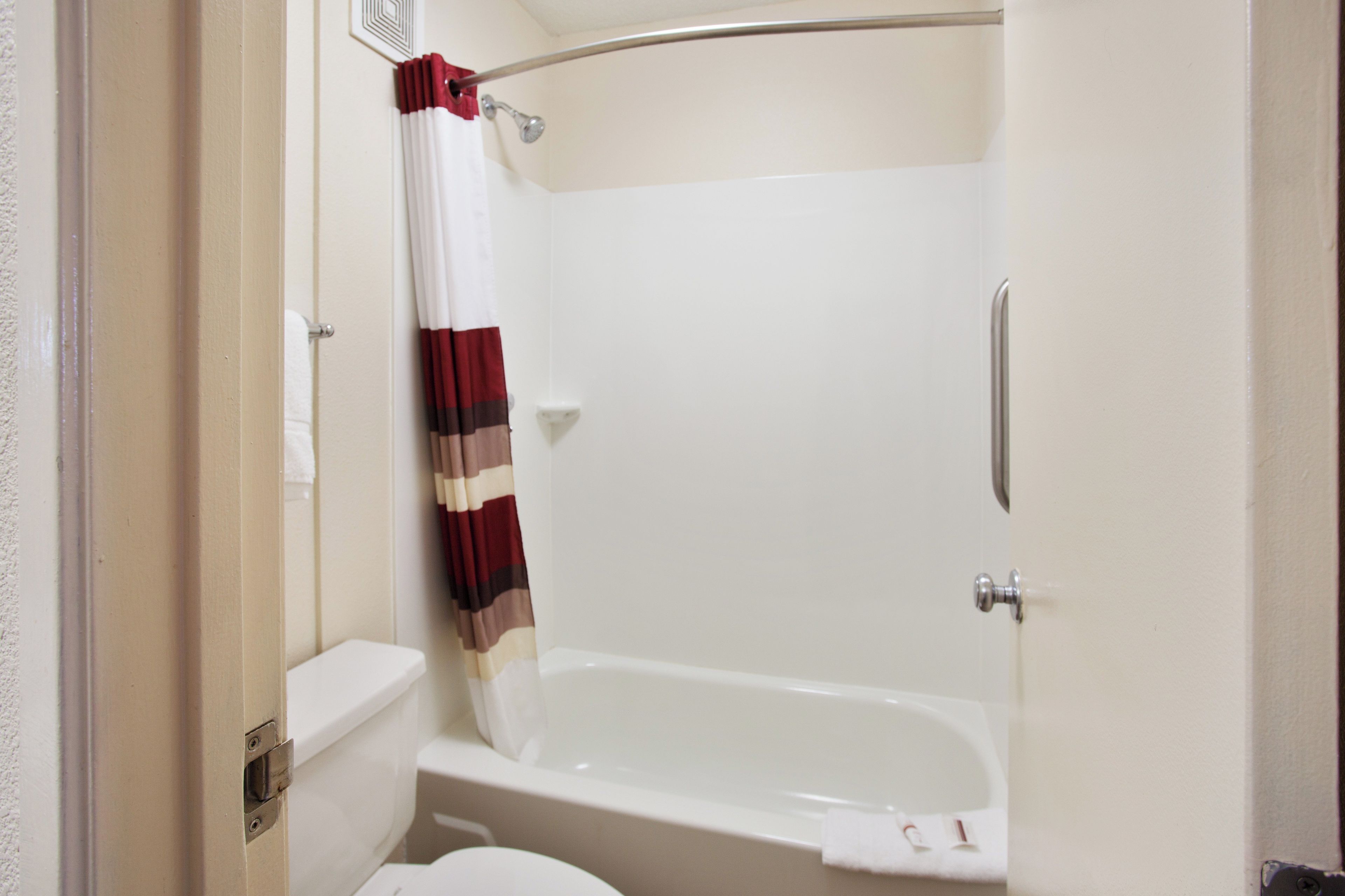 A bathroom with a white bathtub, a shower curtain, and a toilet.