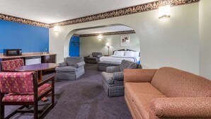 Habitación de hotel con comedor, cama, sofá y televisor.