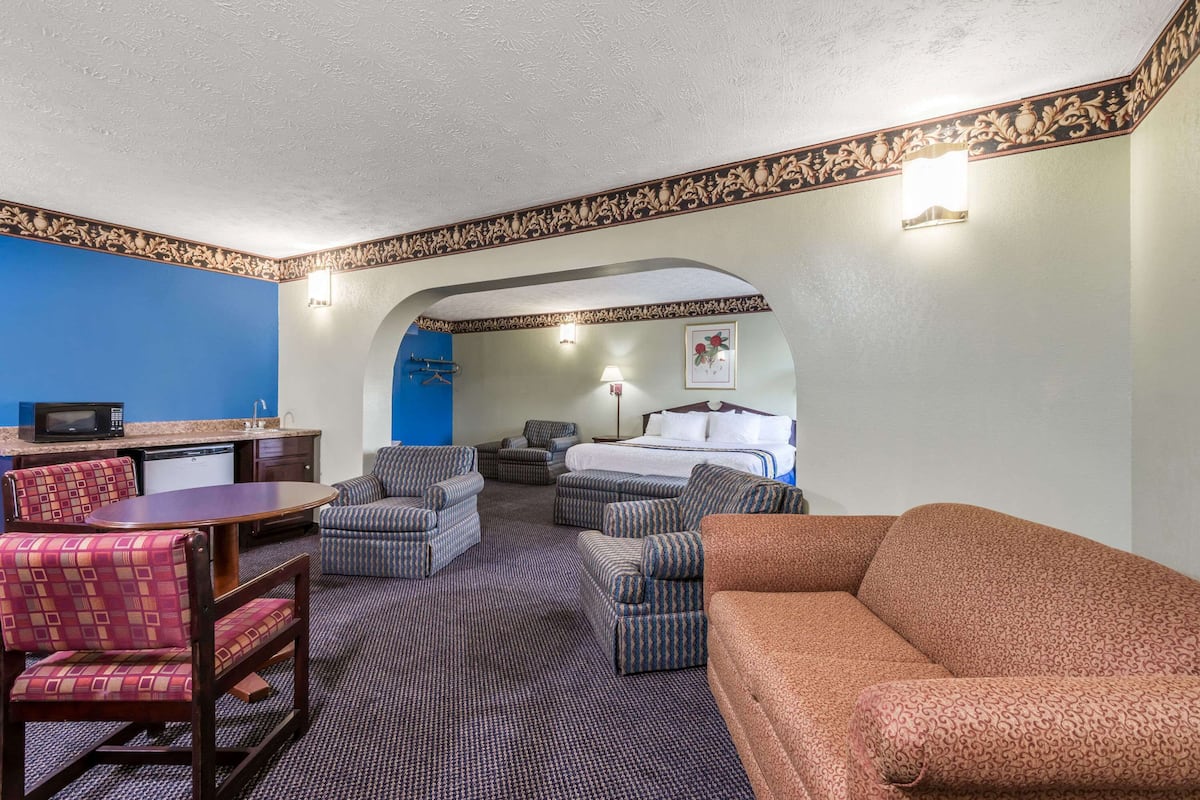 Une chambre d’hôtel comprenant un coin repas, un lit, un canapé et une télévision.