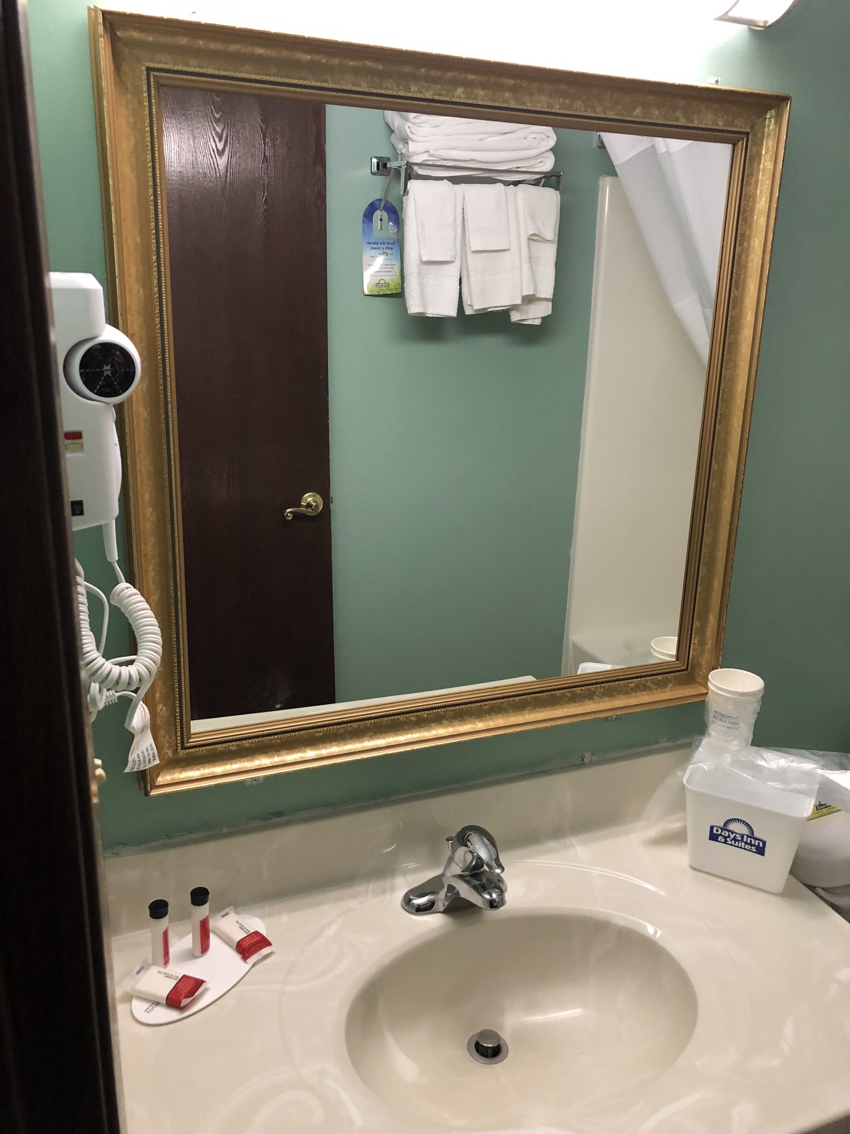A bathroom with a large mirror, a sink, and a towel rack with folded towels.