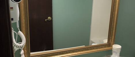 A bathroom with a large mirror, a sink, and a towel rack with folded towels.