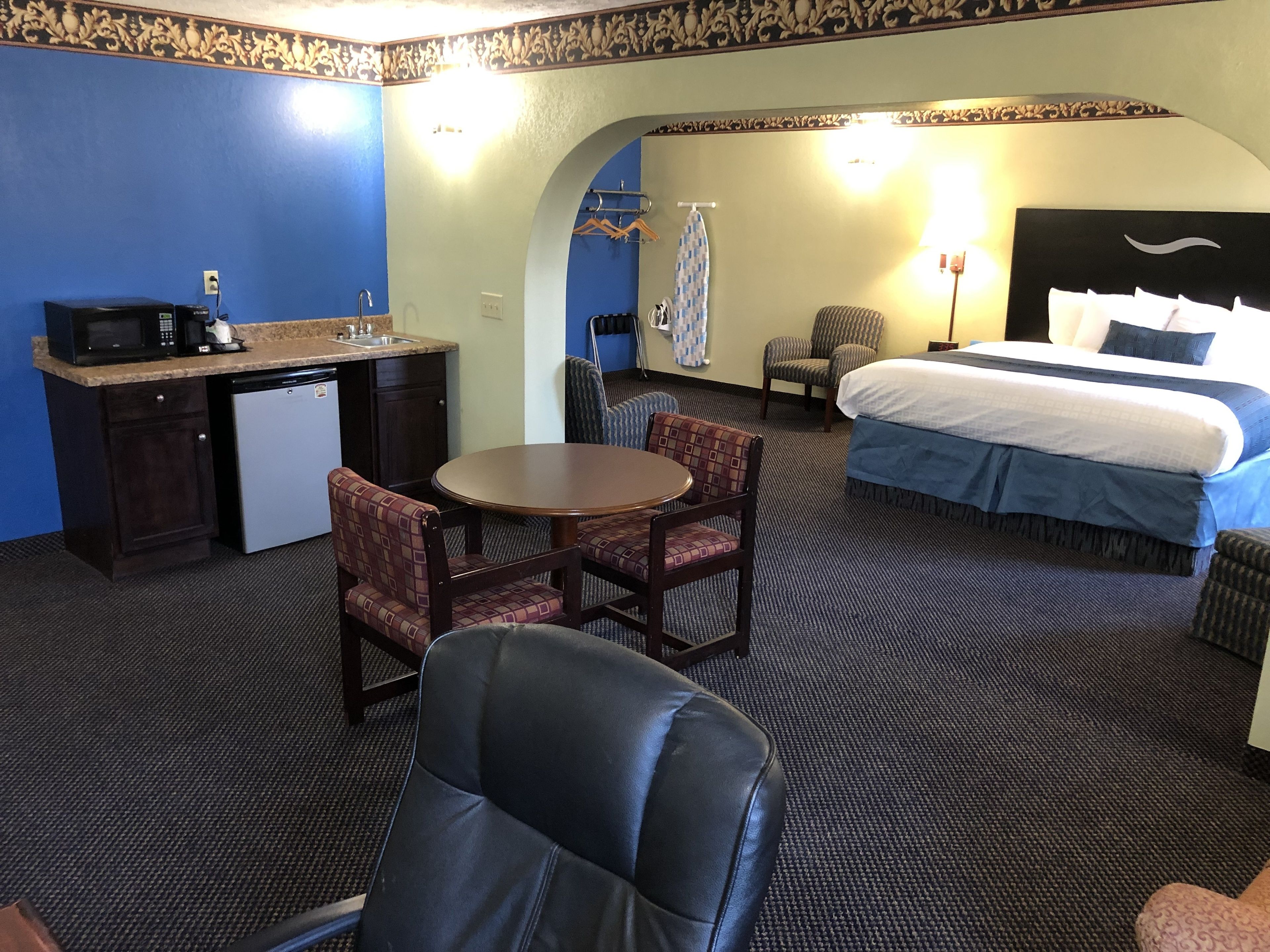 Ein Hotelzimmer mit einem Bett, einem Schreibtisch mit Mikrowelle, einem Sessel und einem kleinen Tisch.