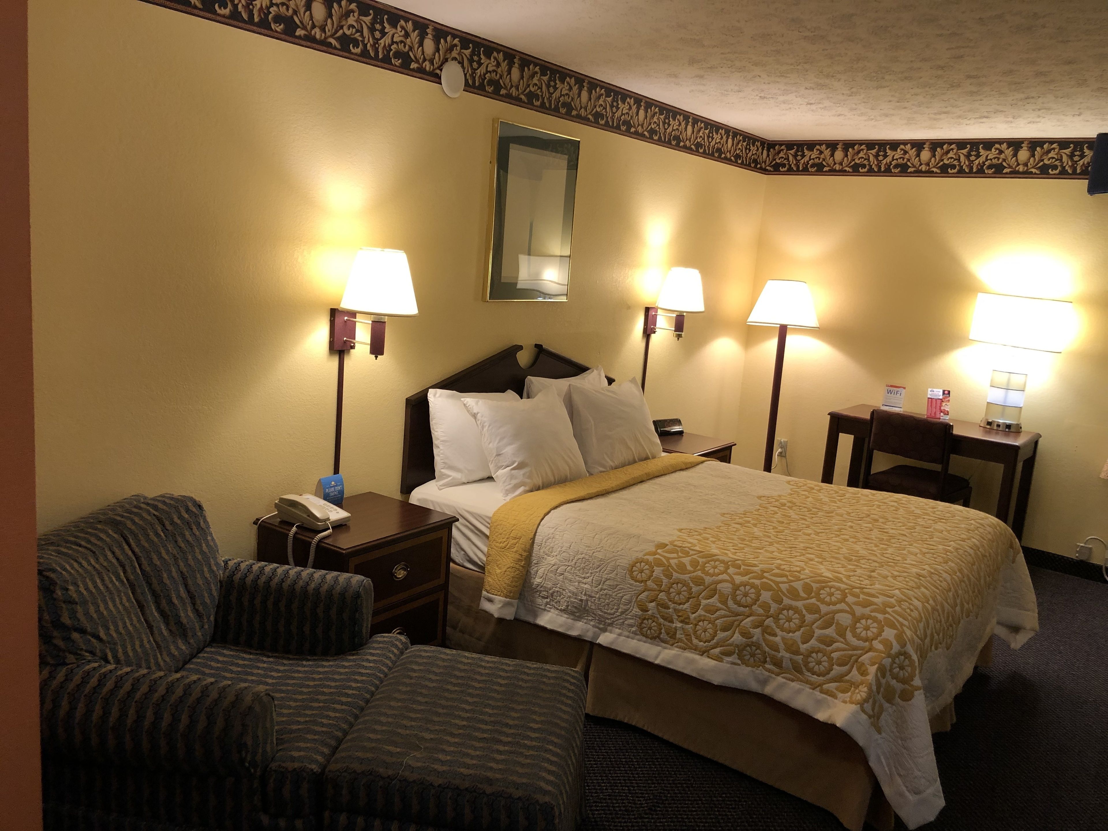 Een hotelkamer met een bed, twee nachtkastjes, een stoel en twee lampen.