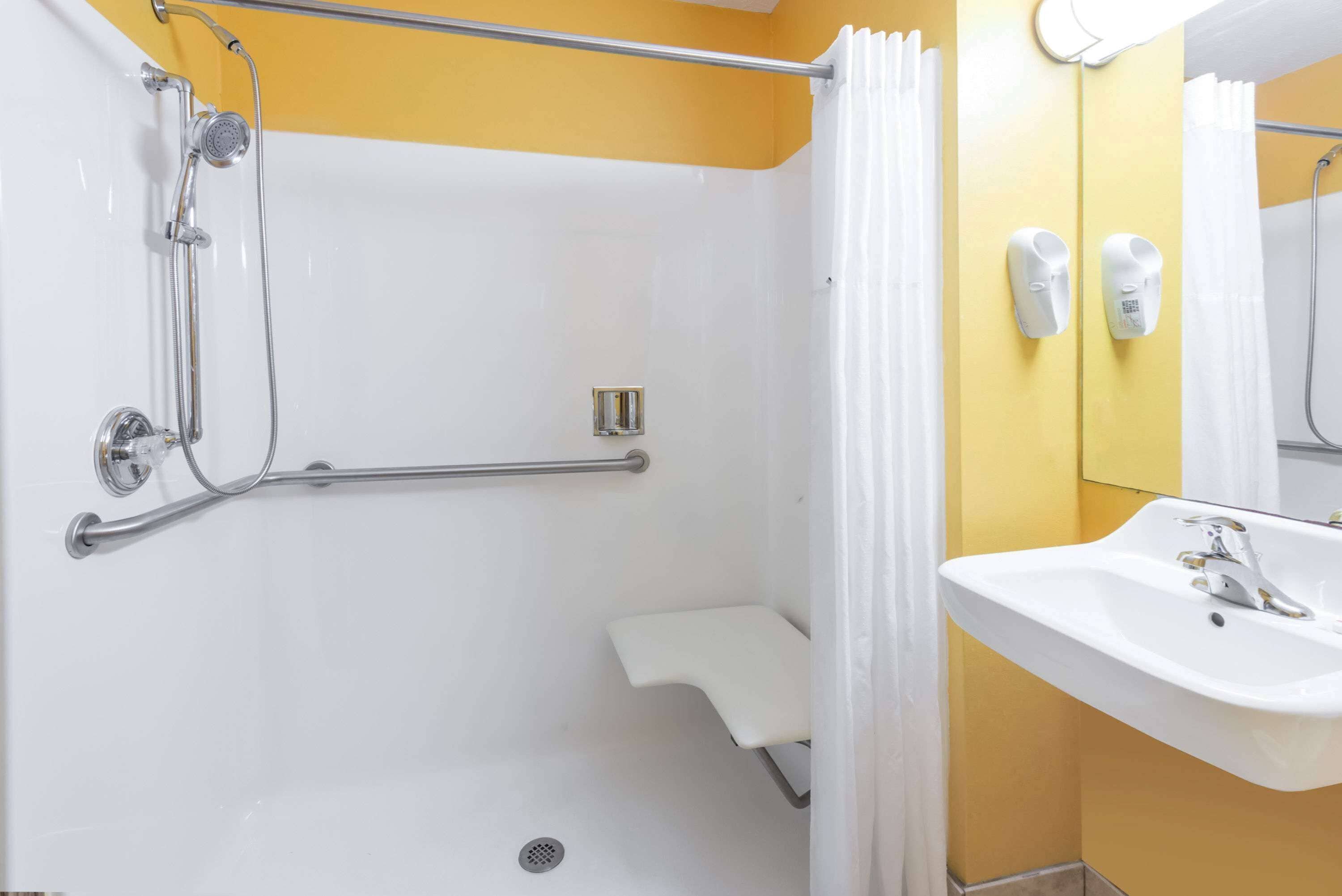 Un baño con ducha, lavamanos y espejo.