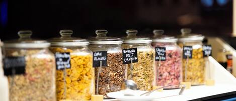 A display of various granola and cereal bars in glass jars with labels.