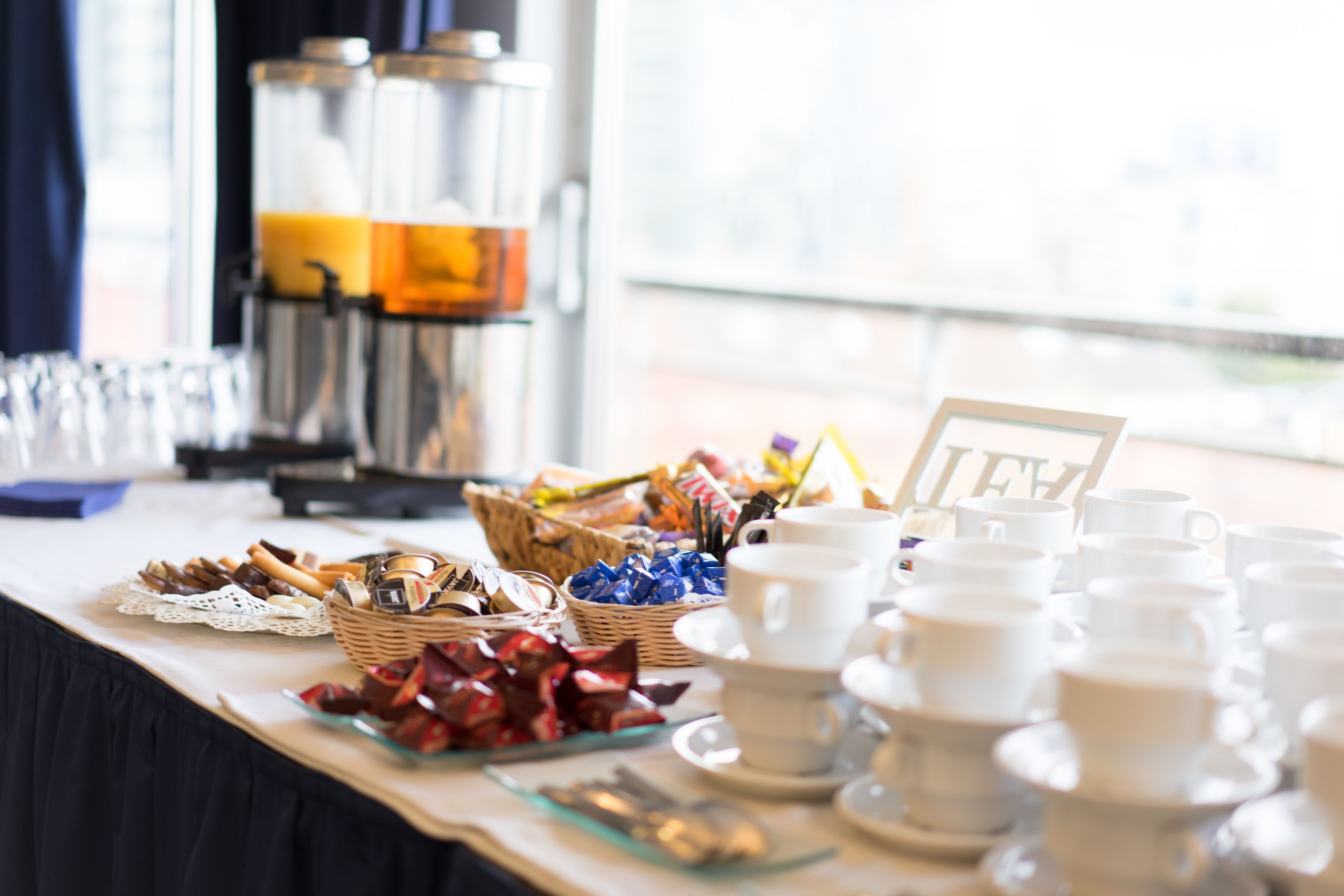 A buffet table with various food items, including bread, pastries, and a coffee station with a coffee pot and cups.