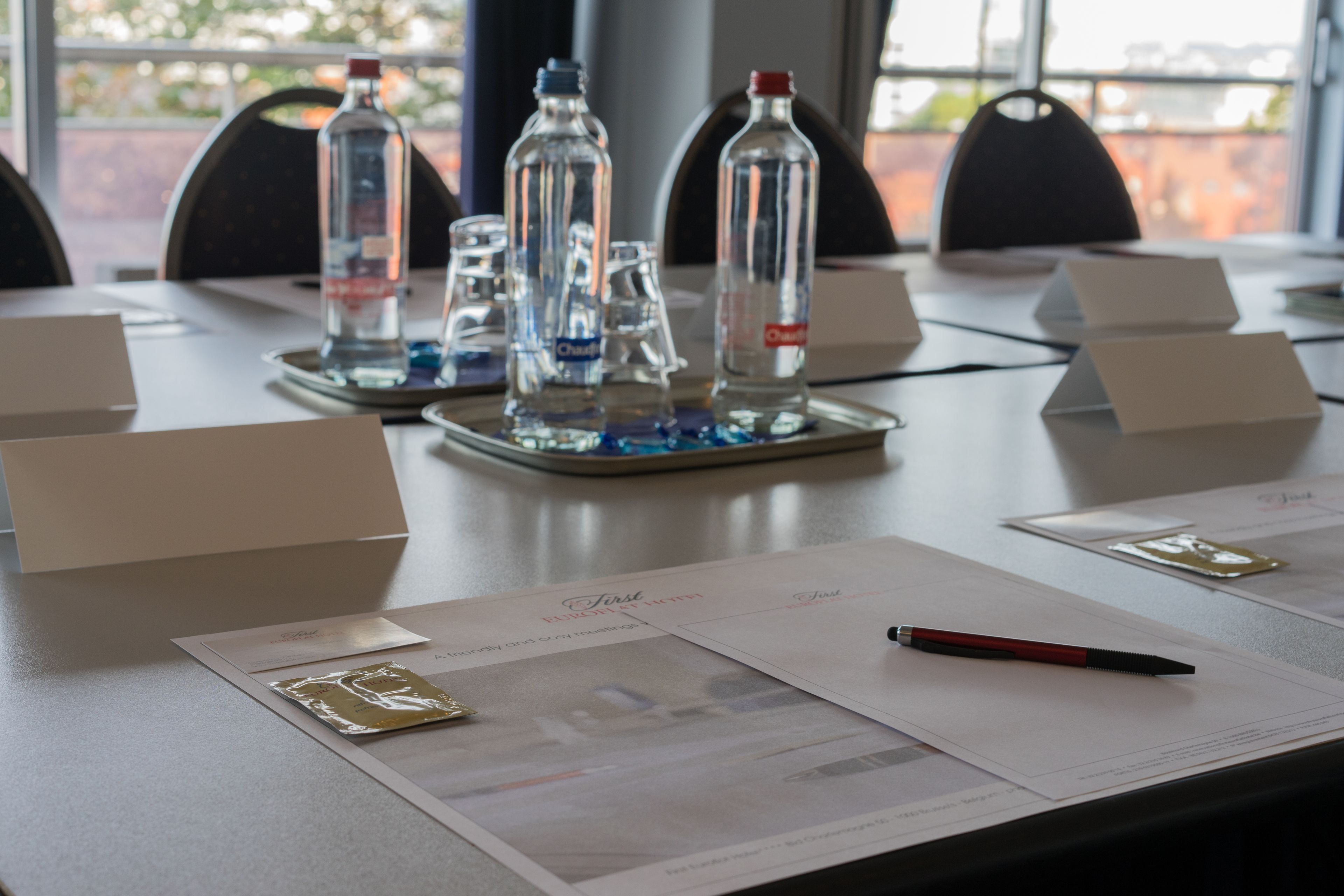 A conference table with name cards, water bottles, and documents.
