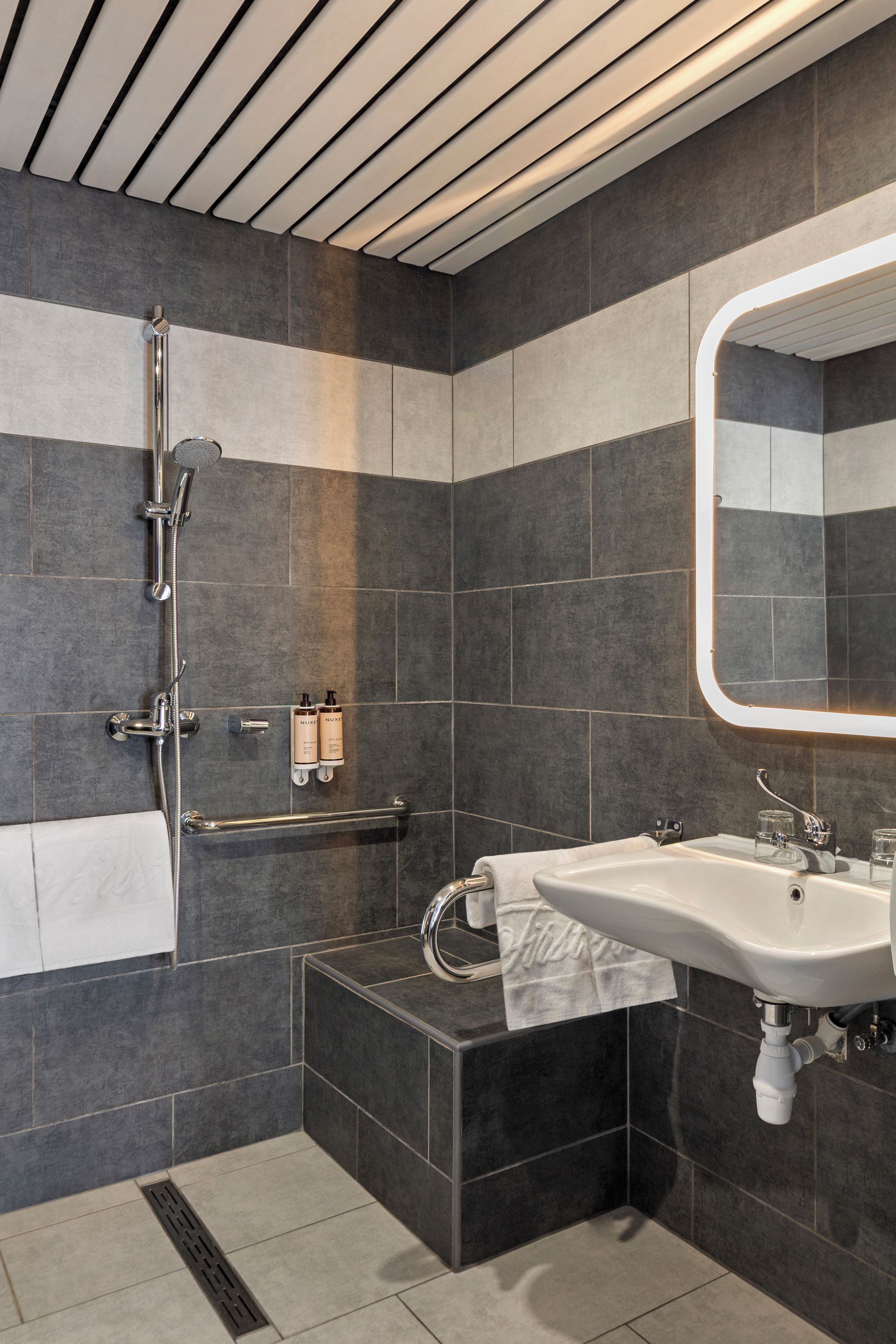A modern bathroom with a shower, a sink, and a mirror.