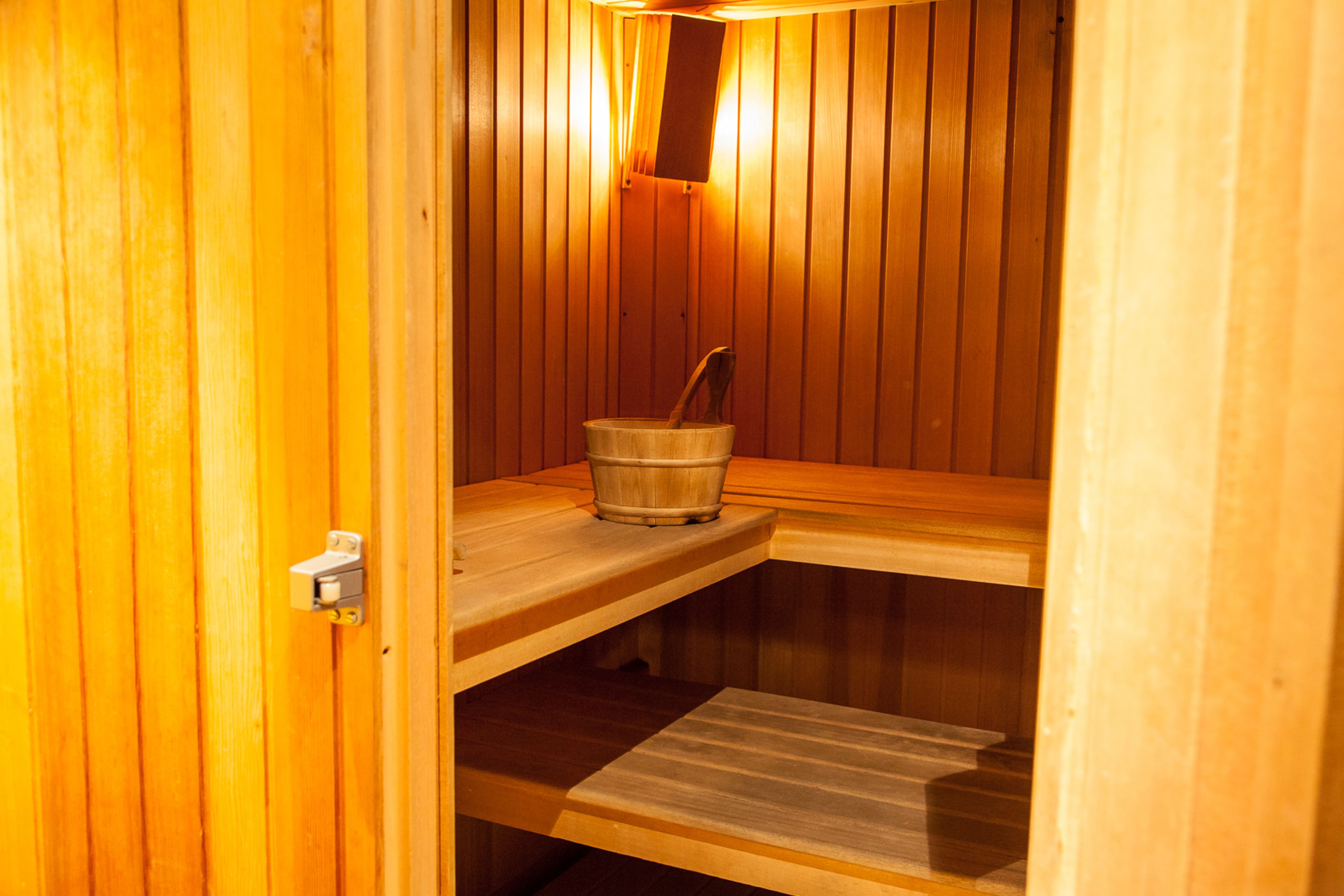 A wooden sauna with benches and a bucket.
