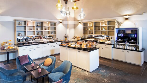 A modern kitchen with a central island, built-in shelves, and hanging pendant lights. - Bilderberg De Bovenste Molen Hotel (Venlo)