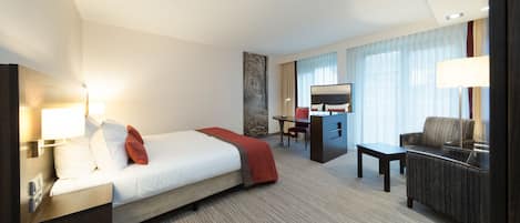 Una habitación de hotel con una cama, un escritorio, una silla y un sofá.