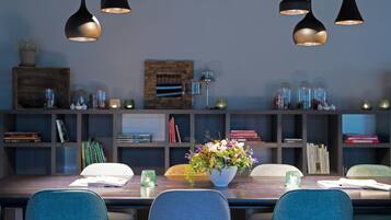 A modern dining area with a wooden table, blue chairs, and black pendant lights.